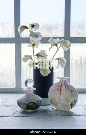 Noch immer leben auf BADEZIMMER FENSTERBANK, MIT ISLE OF WIGHT GLAS PARFÜMFLAKONS UND WEISSE KÜNSTLICHE BLUMEN IN VASE Stockfoto