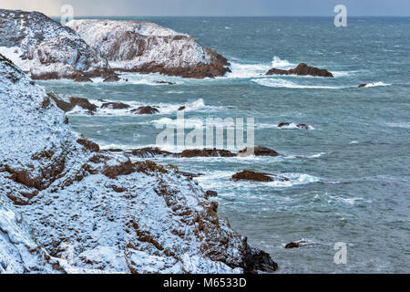 Küste von Moray in Schottland in der Nähe von PORTKNOCKIE IM FEBRUAR WINTER Sturm mit starkem Wind und Schnee bedeckten Klippen Stockfoto