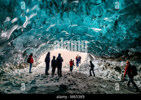 Touristen, die sich in der Crystal Cave, Breidamerkurjokull Gletscher, Island. Emerald Blue Ice und Asche ist Teil der Breidamerkurjokull. Stockfoto
