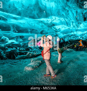 Touristen, die sich in der Crystal Cave, Breidamerkurjokull Gletscher, Island. Emerald Blue Ice und Asche ist Teil der Breidamerkurjokull. Stockfoto