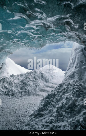 Touristen, die sich in der Crystal Cave, Breidamerkurjokull Gletscher, Island. Emerald Blue Ice und Asche ist Teil der Breidamerkurjokull. Stockfoto