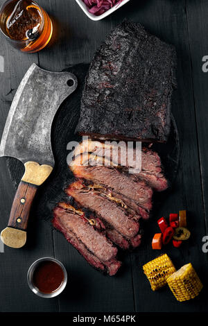 Frische Unterbrust BBQ Beef geschnitten Für gegen einen dunklen Hintergrund mit Sauce servieren, Hot Paprika und Mais. Stockfoto