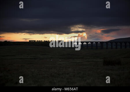 2 Direct Rail Services Klasse 66 Lokomotiven Ribblehead Viadukt bei Sonnenuntergang mit einem Network Rail die Behandlung des Schienenkopfes Zug clearing Blätter im Herbst Pass Stockfoto