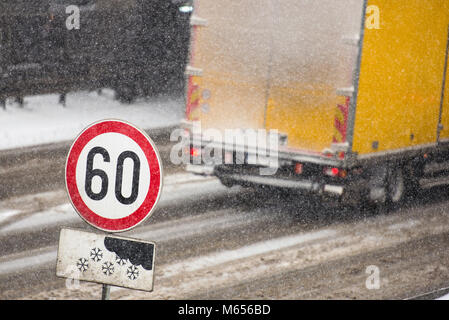 Stau im Winter bei Schneesturm bei schlechter Sicht. Schnee unterzeichnen und Höchstgeschwindigkeit Zeichen, mit einem Stau im Hintergrund auf einer rutschigen Highway co Stockfoto