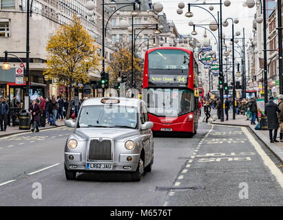 Ein silbernes Londoner Taxi und ein Londoner Bus der Linie N94, die entlang der Oxford Street, London, Großbritannien, fahren Stockfoto