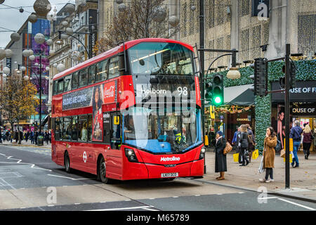 Zwei Frauen warten darauf, an einer Fußgängerkreuzung zu überqueren, als ein Bus der Linie 98 London nach Holborn den Weg entlang der Oxford Street in London nimmt Stockfoto