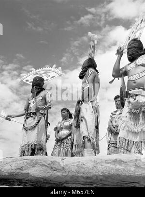 1950s GRUPPE VON NATIVE AMERICAN APACHE INDIANER DURCHFÜHRUNG APACHE TEUFEL TANZ SÜDWESTEN USA-i 1324 HAR 001 HARS TRÄUME AUFREGUNG NIEDRIGEN WINKEL KREATIVITÄT KOPFSCHMUCK PHANTASIE NATIVE AMERICAN KLEINE GRUPPE VON MENSCHEN IM SÜDWESTEN MÄNNER gebürtige Amerikaner RITUAL APACHE B&W SCHWARZ UND WEISS ZEREMONIELLEN TEUFEL TANZ ALTMODISCHE PERSONEN Stockfoto