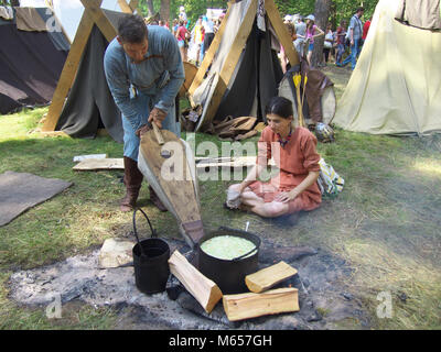 Gnezdovo, Russland - August 09, 2014: Die Menschen in der alten russischen Kleidung schüren das Feuer im Herd verwenden Sie den Faltenbalg auf dem historischen Festival Stockfoto