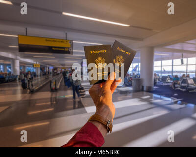 Hand mit zwei amerikanischen Pässe vor einer Fluggesellschaft Boarding Gate Stockfoto