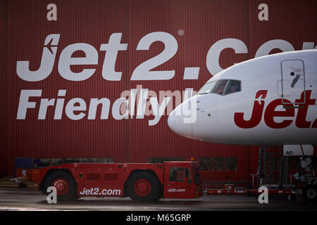 Manchester Airport Jet 2 Wartung hanger Boeing 757 in den Jet2 Urlaub Lackierung an einen Schlepper angeschlossen Stockfoto