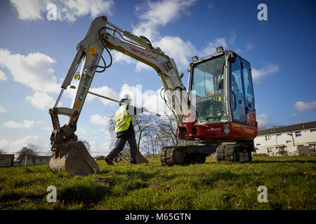 Arbeiter auf der Baustelle neben einem Mini Bagger Stockfoto