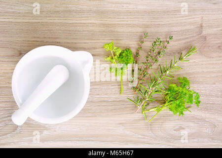 Weißer Keramik Mörser und Stößel mit frischen Kräutern in Flach format und schoss in natürlichem Licht Stockfoto