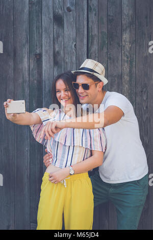 Junge moderne hipster Paar unter selfie mit smart phone gegen die Holzwand. Liebe- und Technologiekonzepte Stockfoto
