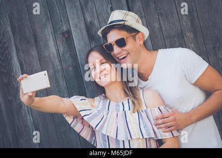 Junge moderne hipster Paar unter selfie mit smart phone gegen die Holzwand. Liebe- und Technologiekonzepte Stockfoto