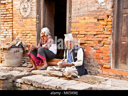 BHAKTAPUR, Nepal - Mai 20: Alte Frau und Mann ihre Häuser miteinander verflochten am 20. Mai 2013, Bhaktapur, Nepal Bhaktapur ist einer von 3 königlichen Städte in der Ka Stockfoto