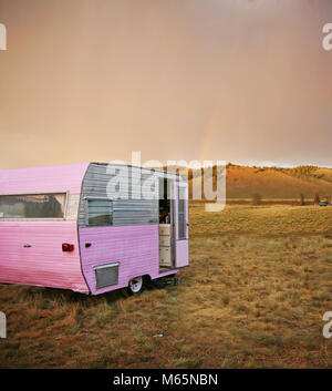 Süße vintage Camper Trailer in der Sägezahn Mountain Range in einem desolaten Lagerplatz im Sommer regen Sturm mit einem Regenbogen in der Ferne getönten w Stockfoto