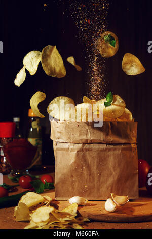 Flying Chips auf einem dunklen Hintergrund. Das Bild kann in der Werbung Verpackungen aus Papier oder einen Artikel über ungesunde Lebensmittel verwendet werden. Stockfoto