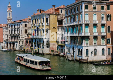 Wasserbus, Dampfschiff (Vaporetto), Fährschifffahrt. Typische Gebäudefassaden am Canal Grande. Zauberhaftes Venedig, Italien, Europa, EU. Blauer Himmel. Stockfoto