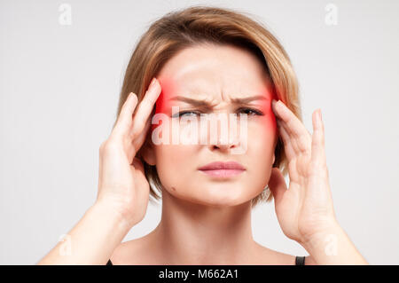 Frau leidet unter schrecklichen Kopfschmerzen und komprimiert den Kopf mit den Fingern Stockfoto