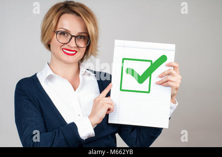Schöne Business woman holding leeres Papier mit Haken oder zugelassenen Symbol Stockfoto