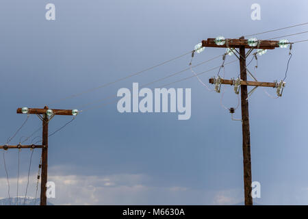 Ein paar alte hölzerne elektrischen Säulen mit Kopie Raum zwischen Ihnen und Stromleitungen gegen stürmischen Himmel Stockfoto