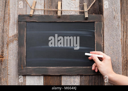 Hand mit weißer Kreide auf leeren Tafel Stockfoto