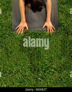 Junge kaukasier Frau übt Yoga im Central Park in New York City während trägt ein blaues Top, schwarze Leggings und barfuss Stockfoto