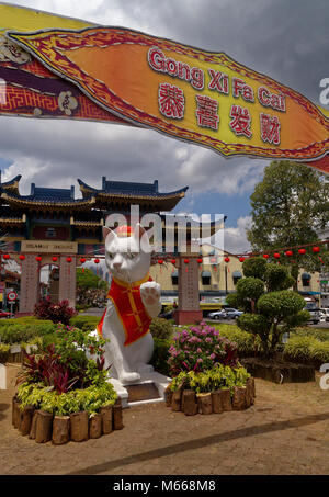 Das Wahrzeichen white cat Statue auf Jalan Pdungan, Kuching, Sarawak, Malaysia, in Rot für das chinesische Neujahr gekleidet Stockfoto