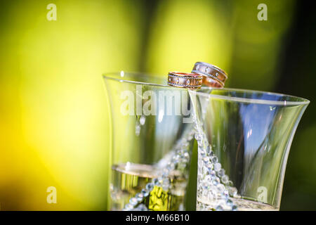 Trauringe liegen auf dem Gläser Champagner Stockfoto