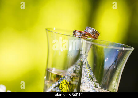 Trauringe liegen auf dem Gläser Champagner Stockfoto
