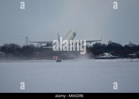 Schnee bedeckt. Flybe Embraer ERJ-195 nehmen Sie am Flughafen London Southend in Schnee während des Tieres aus dem Osten wetter Phänomen Stockfoto