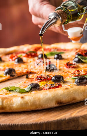 Koch und Pizza. Koch gießen Olivenöl auf Pizza im Hotel oder im Restaurant. Stockfoto