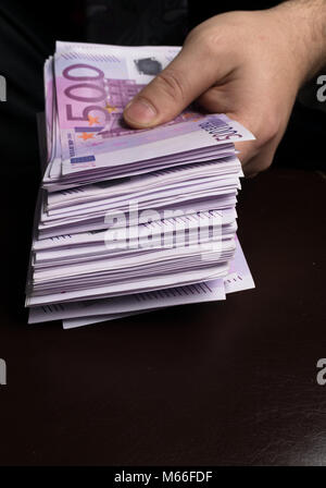Mann in Herren Anzüge. Bestechung und Korruption mit Euro-banknoten. Mann hält ein Bündel von Euro-bargeld Stockfoto