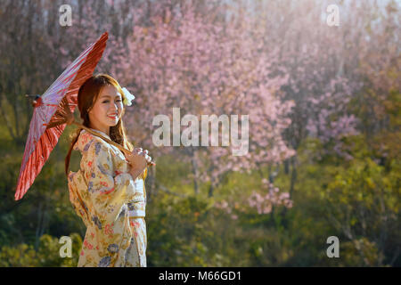 Porträt einer Frau, die in einem Cherry Orchard tragen traditionelle japanische Kimono Stockfoto