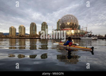 Downtown Vancouver, British Columbia, Kanada - 28. Januar 2017 - Frau Kajakfahren in der Nähe von Science World in False Creek während einer lebhaften winter Sonnenuntergang. Stockfoto