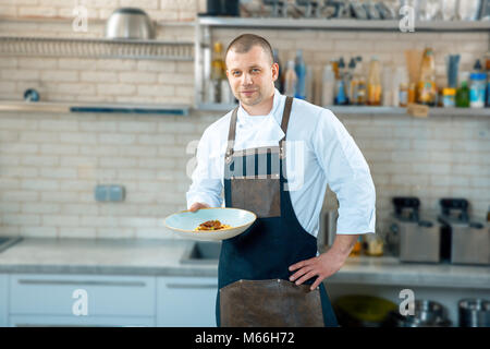 Gerne männliche Küchenchef präsentiert die Schüssel in der gewerblichen Küche Innenraum Stockfoto