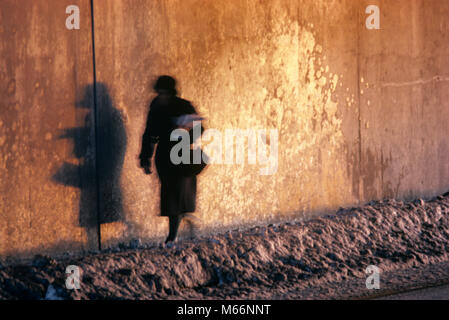 Anonyme SILHOUETTE FRAU WANDERN AUF VERSCHNEITER Straße der Stadt werfen Schatten auf der Wand kw8751 und 001 HARS PERSONEN Stockfoto