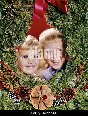 1960 lächelnde blonde Junge und Mädchen Bruder und Schwester PEEKING OUT VON DER MITTE DES CHRISTMAS WREATH - KX3225 HAR 001 HARS BROTHERS STUDIO SHOT HOME LEBEN FREUNDSCHAFT DRINNEN GESCHWISTER SPIRITUALITÄT SCHWESTERN NOSTALGIE ZWEISAMKEIT 3-4 JAHRE 5-6 JAHRE GLÜCK KOPF UND SCHULTERN FRÖHLICHER AUFREGUNG WACHSTUM GESCHWISTER LÄCHELN DEZEMBER VERBINDUNG FROHEN DEZEMBER 25 JUNGEN MÄNNER PEEKING OUT KAUKASISCHEN ETHNIE ALTMODISCH Stockfoto