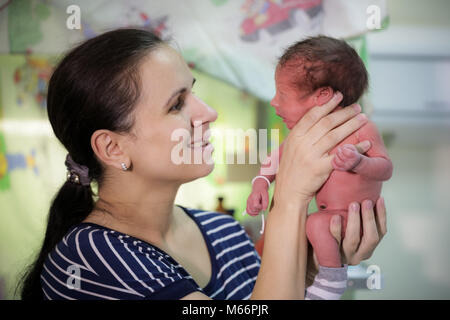 Mama hält ein neugeborenes Baby in ihren Armen Stockfoto