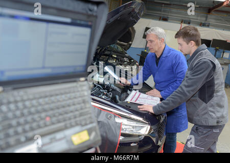 Schüler mit Lehrer, die Reparatur eines Autos während der Lehrzeit Stockfoto