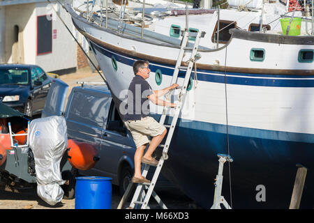 Man Klettert eine Leiter auf einem Boot auf steht im Trockendock, aus Wasser in eine Bootswerft. Boot Wartung. Stockfoto