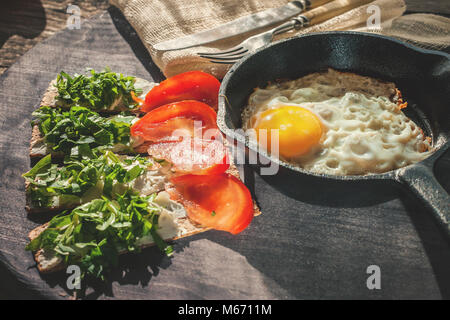 Ein gesundes Land Frühstück mit Rührei in einer runden Wanne und knuspriges Brot mit weicher ricotta Käse und frischen Kräutern. Das Konzept der gesunden Ernährung Stockfoto