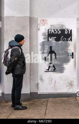 Berlin, Mitte, Alexanderplatz. Senior älteren Mann mit Rucksack schaut auf Street Art - Silhouette der Mann mit Aktentasche & Pass mir von Kop Inschrift Stockfoto