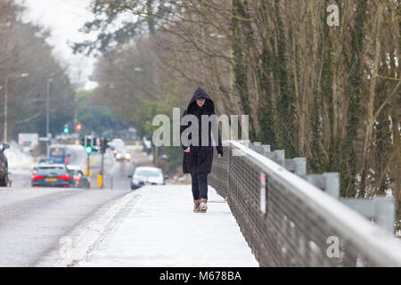 Ashford, Kent, Großbritannien. März 2018. Wetter in Großbritannien: Bestie aus dem Osten. Eine leichte Schneedusche heute Morgen im Stadtzentrum von Ashford in Kent mit lokalen Mitarbeitern, die die potenziell gefährlichen Gehwege und Gehwege durchgraten. Das Wetter wird sich voraussichtlich heute und bis Freitag verschlechtern. Die aktuelle Temperatur liegt bei -4 Grad, fühlt sich aber wie -11 Grad an Abgebildet ist eine Frau, die auf der Fußgängerbrücke über die M20 im Schnee spaziert. Foto: PAL-Bilder / Alamy Live News Stockfoto