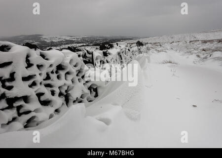 UK Wetter: Ilkley Moor, West Yorkshire, UK. 1. März 2018. Schneeverwehungen auf der Lee-seite von steinmauern wie starke Winde beginnen - Tier aus dem Osten. Rebecca Cole/Alamy leben Nachrichten Stockfoto