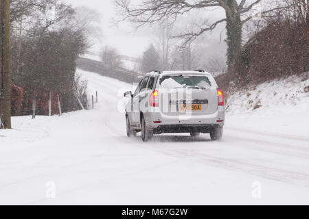 Titley, Herefordshire, UK-Donnerstag, 1. März 2018 - ein Auto fährt durch Titley Dorf auf dem schneebedeckten B 4355 zwischen Kington und Presteigne durch die england-wales Grenze - Sturm Emma feine nasser Schnee durch starke Winde zu den ländlichen Gemeinden mit mehr Schnee Prognose über Nacht geblasen hat. Foto Steven Mai/Alamy leben Nachrichten Stockfoto