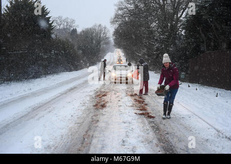 Southampton, Großbritannien. 1. März, 2018. Donnerstag, 1. März 2018 UKsnow West Wellow Southampton, England. Gemeinschaft spirt, ein paar Freunde, die in der Nähe der A36 live Gießen grit auf der Straße und hilft gestrandeten push Autofahrer auf einem der vielen Hügel entlang der Route in Richtung Southampton Rubrik von Salisbury. Sturm Emma kombiniert mit dem "Tier aus dem Osten' hits West Wellow, Romsey Hampshire am späten Nachmittag verursacht Chaos auf der A36 die Hauptroute von Southampton nach Salisbury. Autos und Lastwagen auf die vielen Hügel blockiert Verkehr stecken geblieben. Credit: PBWPIX/Alamy leben Nachrichten Stockfoto