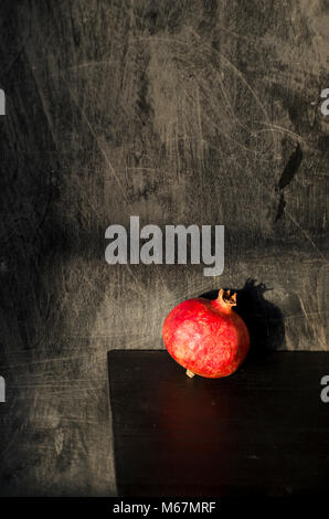 Still-life nature morte mit roter Granatapfel auf schwarzem Holz- Hintergrund Stockfoto