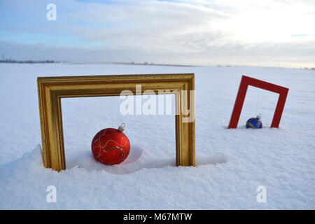 Zwei Bilderrahmen und Christbaumkugeln auf Schnee auf dem Feld Stockfoto