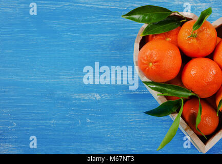 Orangen in einer herzförmigen Box auf einem blauen vintage Holz- Hintergrund Stockfoto